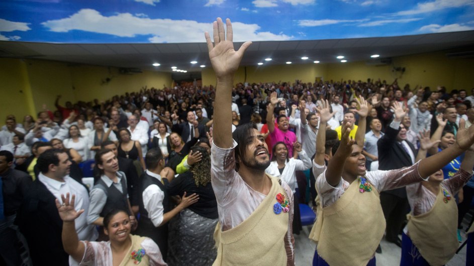 un templo pentecostal esta lleno de fieles, que levantando sus manos miran al frente jubilosos